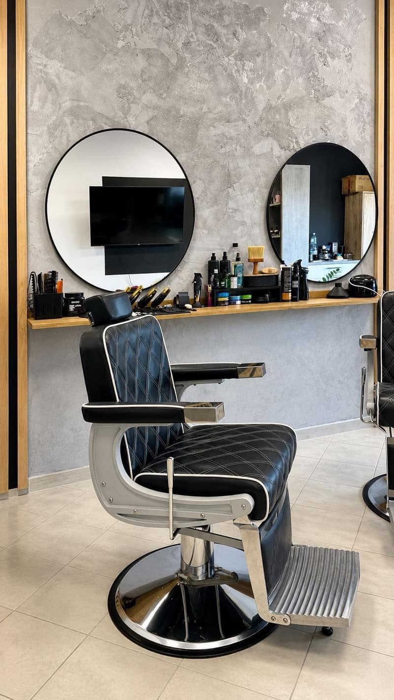 Stanowisko barberskie z czarnym fotelem, lustrem i półką z kosmetykami