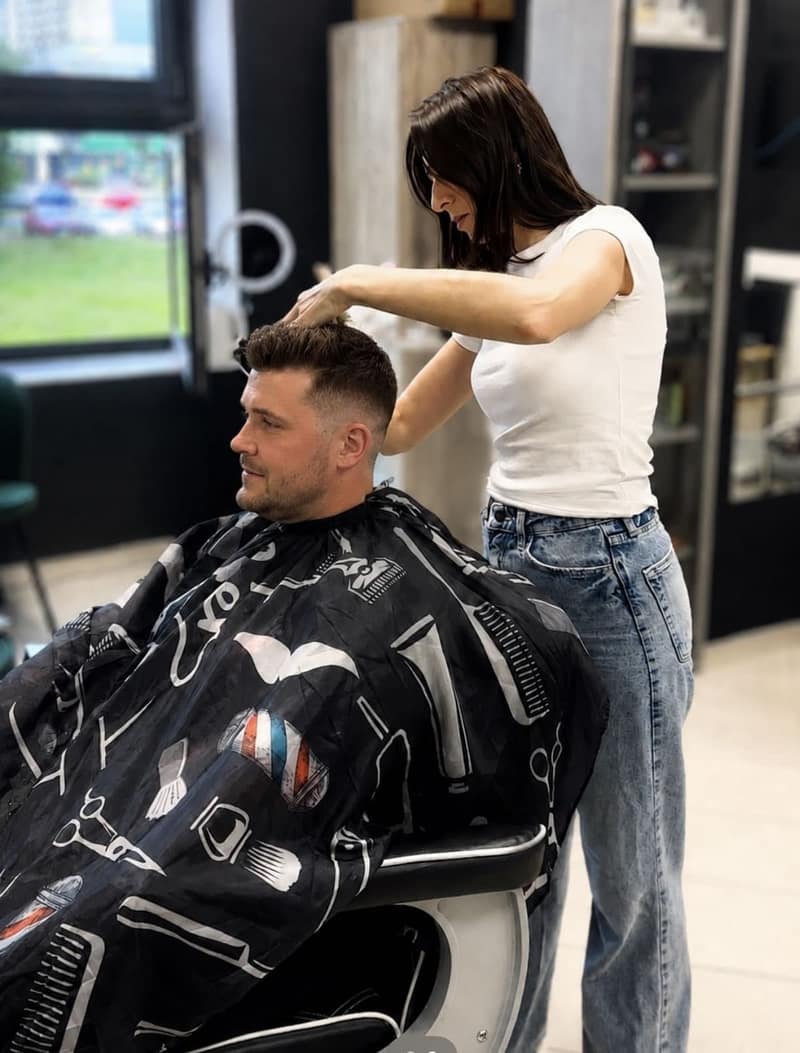 Barberka modeluje włosy klienta podczas męskiego strzyżenia w ALIA Barber Tychy